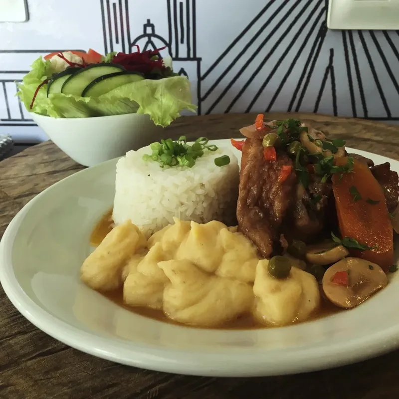 Prato de carne ao molho com cenoura e cogumelos, purê e arroz, com uma tigela de salada de folhas ao lado.