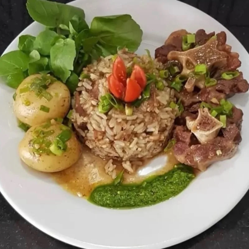Prato do dia servido no almoço do Família Paulista: ossobuco com o osso à mostra e cebolinha, arroz temperado moldado, batatas cozidas, agrião e um fio de molho verde.