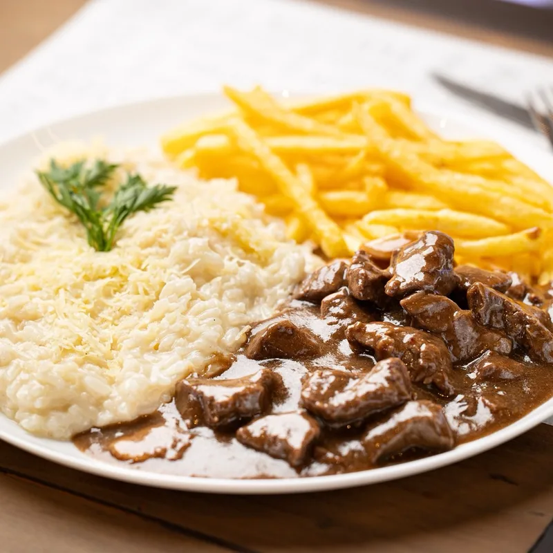 Prato do dia servido no almoço do Família Paulista: strogonoff de carne ao molho escuro, arroz coberto de queijo ralado com salsinha e batatas fritas.